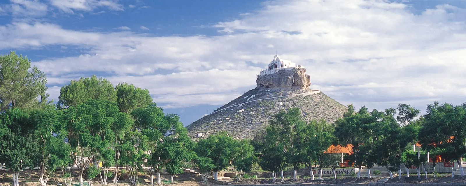 La capilla del Santo Madero encaramada sobre el peñasco que domina Parras de la Fuente, con la arboleda verde del oasis al pie del cerro