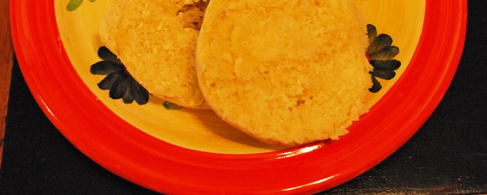 Gorditas de nata doradas servidas en un plato decorado, una partida a la mitad mostrando su miga esponjosa