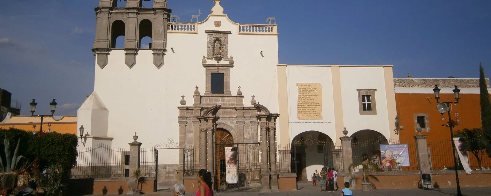La parroquia de San Francisco de Asís en Comonfort: fachada encalada con portada de cantera labrada y campanario, vista desde el atrio