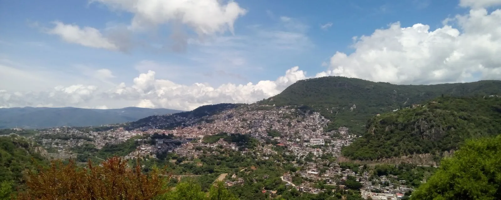 Taxco desde el mirador: el caserío blanco cubriendo la ladera del cerro, con la torre de Santa Prisca destacando en el centro del pueblo