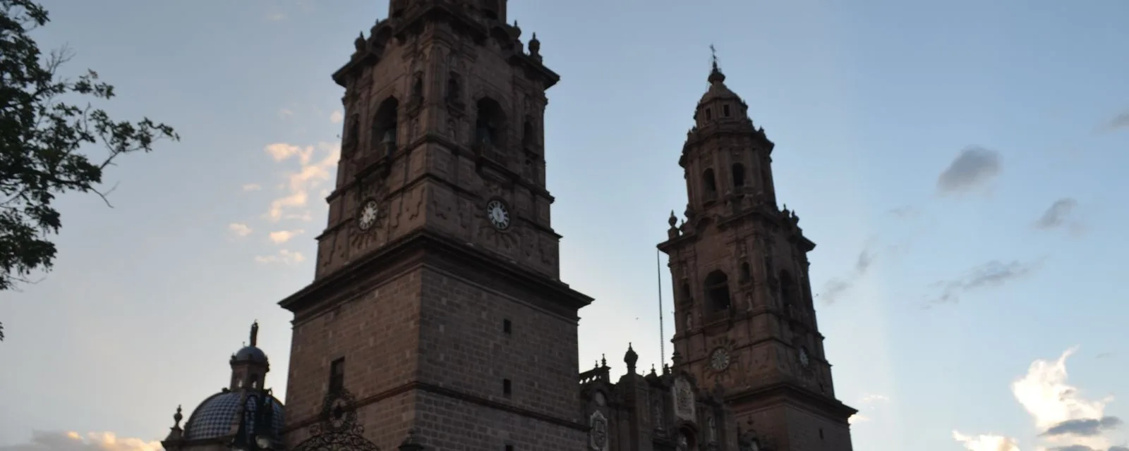 Las dos torres de cantera de la Catedral de Morelia al atardecer, recortadas contra un cielo que va del azul al rosa