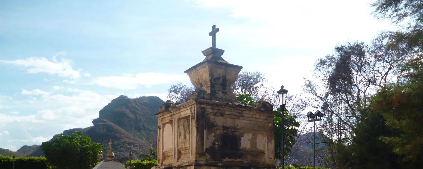 Una de las capillas de barrio de Tlayacapan, con su cruz de piedra sobre el remate, y los cerros del valle recortados al fondo