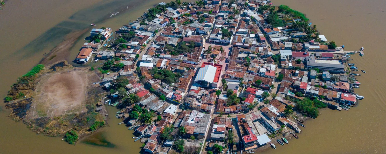 La isla de Mexcaltitán desde el aire: un óvalo de casas con calles trazadas en anillos y cruz, rodeado por completo de agua