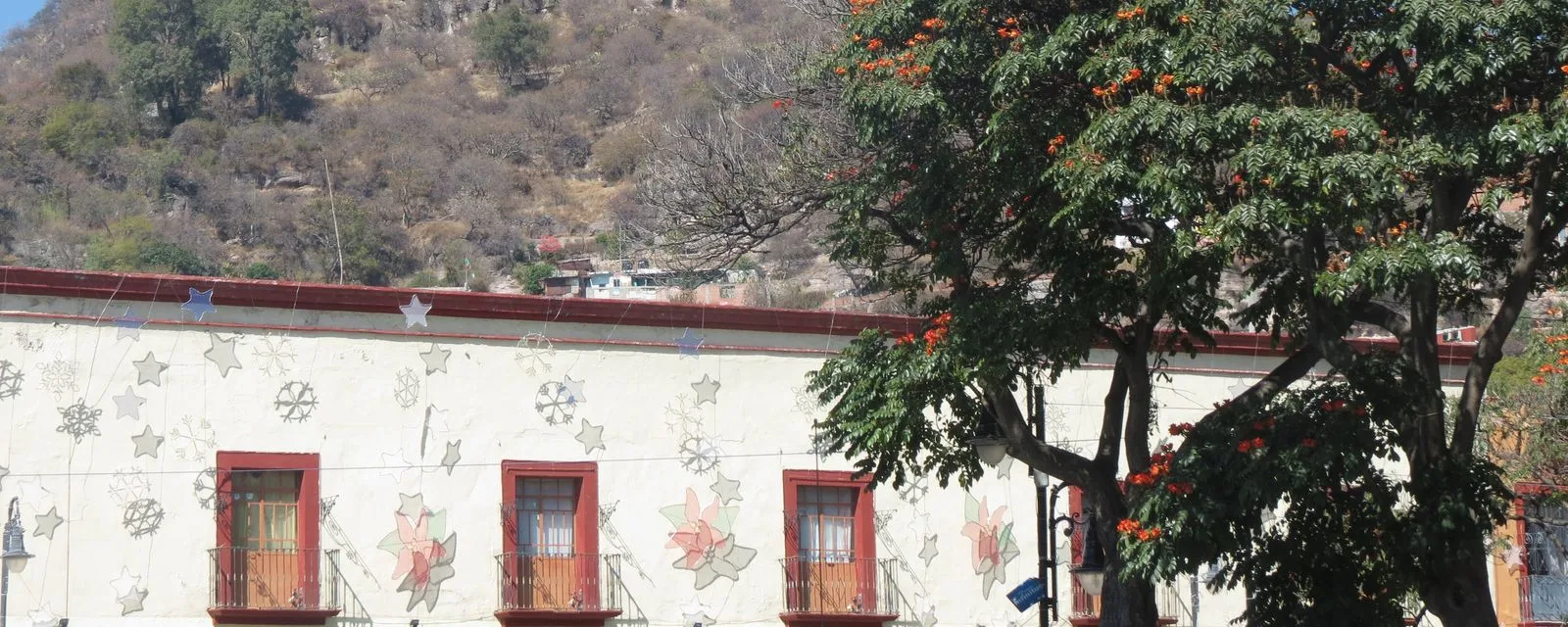 Una fachada de Atlixco decorada con esgrafiados de flores y estrellas de colores, con balcones de herrería y el cerro de San Miguel levantándose detrás