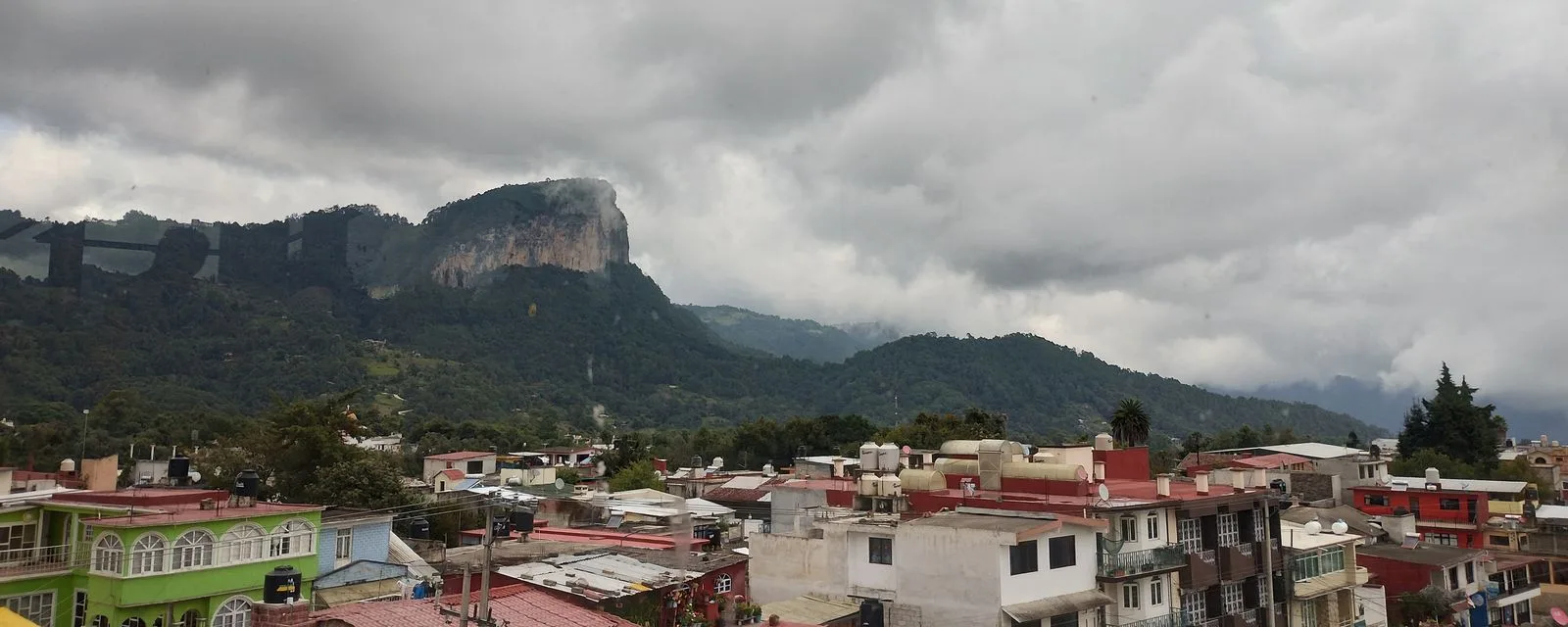 El Cerro Cabezón alzándose entre nubes sobre los techos de Tlatlauquitepec, con la sierra verde extendiéndose a los lados
